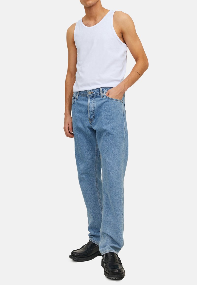 Hvid bomulds tanktop parret med lyseblå afslappede jeans. Jeansene har et klassisk fem-lomme design og subtile falmninger.