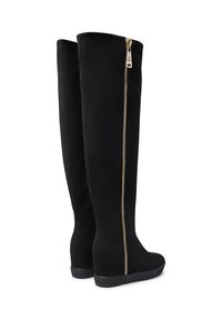 Stivali neri fino al ginocchio con zeppa, dotati di zip laterale dorata e suola in gomma texture, mostrati da dietro e di lato su sfondo bianco.