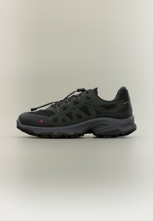 Baskets de sport noires et vert foncé avec empeigne en mesh, semelle renforcée et fermeture à lacets avec système de blocage sur un fond uni clair.