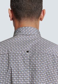 Gekleed overhemd met een geometrisch patroon in blauw, wit en grijs; zachte stof; standaard kraag met knoopdetail.