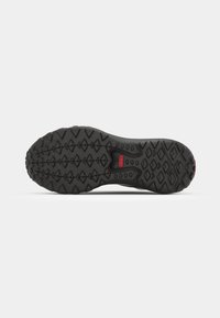 Black rubber shoe sole featuring a textured tread pattern with diamond shapes and a red accent in the center.