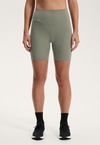 Höga, olivgröna shorts med en mjuk, elastisk textur, som har en minimalistisk design utan synlig hårdvara eller mönster.