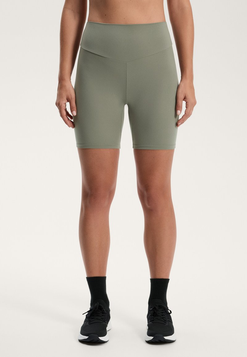 Höga, olivgröna shorts med en mjuk, elastisk textur, som har en minimalistisk design utan synlig hårdvara eller mönster.