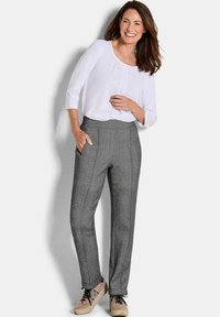 Grijze geruite broek met een getailleerde fit, hoge tailleband en zijzakken, gecombineerd met een witte blouse en beige sneakers.