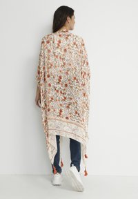Kwiatowy kimono z przejrzystego materiału w pomarańczowe, fioletowe i zielone wzory; posiada frędzle u dołu i kontrastowe wykończenie na brzegach.