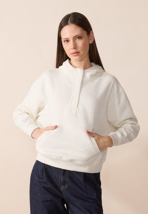 Felpa bianca con mezza zip, tasca frontale e polsini a costine. Tessuto morbido con una vestibilità rilassata, abbinata a pantaloni in denim scuro.