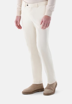 Weiße Baumwollmischhosen im Slim-Fit, mit Gürtelschlaufenbund und klassischem Vorderseitentaschen-Design. Kombiniert mit beige Wildlederstiefeln.