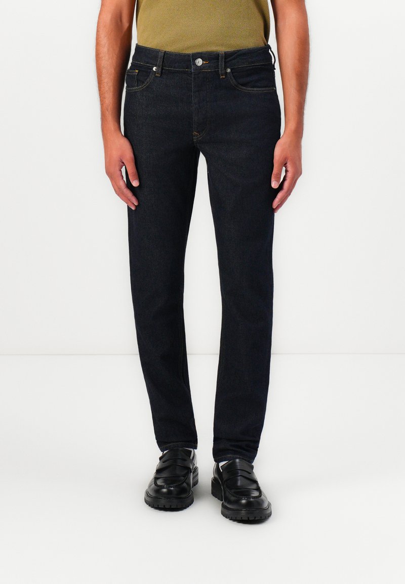 Dunkelblaue Denim-Jeans mit schlankem Schnitt, klassischem Fünf-Taschen-Design und kupferfarbener Naht. Der Bund verfügt über einen Knopfverschluss.