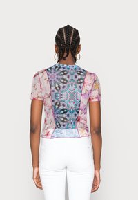 Top transparente de manga corta con patrones florales y geométricos multicolores, diseño ajustado y ribetes en contraste a lo largo de las costuras.