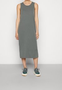 Grijze mouwloze midi jurk met een ronde halslijn, voorzien van een rechte snit en zijsplitten, gecombineerd met teal sneakers. Minimalistisch ontwerp.