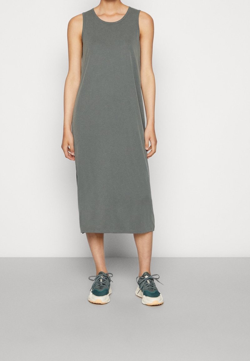 Grijze mouwloze midi jurk met een ronde halslijn, voorzien van een rechte snit en zijsplitten, gecombineerd met teal sneakers. Minimalistisch ontwerp.