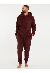 Bordeaux loungewear set van fleecemateriaal, bestaande uit een hoodie met een voorzak en elastische cuffs, samen met bijpassende broeken met geribde zomen.