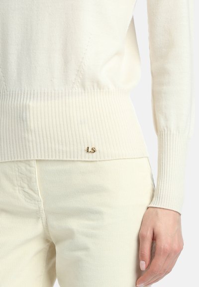 Kremowy sweter z prążkowanego dzianiny o dopasowanym kroju, z subtelnym złotym logo "LS" na linii brzegu i długimi rękawami.