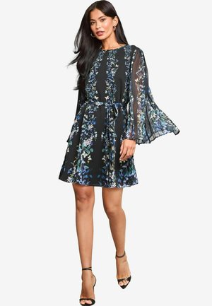 Schwarz mit floralem Druck versehenes Kleid mit langen, durchsichtigen Glockenärmeln, tailliertem Bund und ausgestellt Rock. Verfügt über eine zarte Schleife in der Taille.
