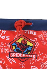 Bañador rojo con una cinturilla azul, que presenta un gráfico de Spiderman y patrones de texto en blanco. Incluye un cierre con cordón ajustable.