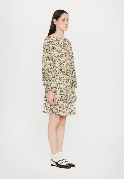 Floral dress in light fabric with long sleeves, featuring a cream base, pink and green flowers, and a cinched waist. Brown shoes with white accents.
