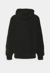 Sort fleece hoodie med en tekstureret overflade, lange ærmer og hætte. Manchetter og bund i ensfarvet sort stof. Ingen frontdetaljer er synlige.