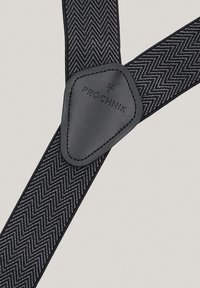 Czarne szelki w wzór jodełki z skórzaną naszywką z logo "Próchnik"; posiadają regulowane paski i mocne klipsy.