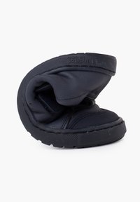 Scarpa nera piegata con tomaia testurizzata e suola liscia. Presenta una fodera imbottita e dettagli di cucitura visibili lungo il bordo.