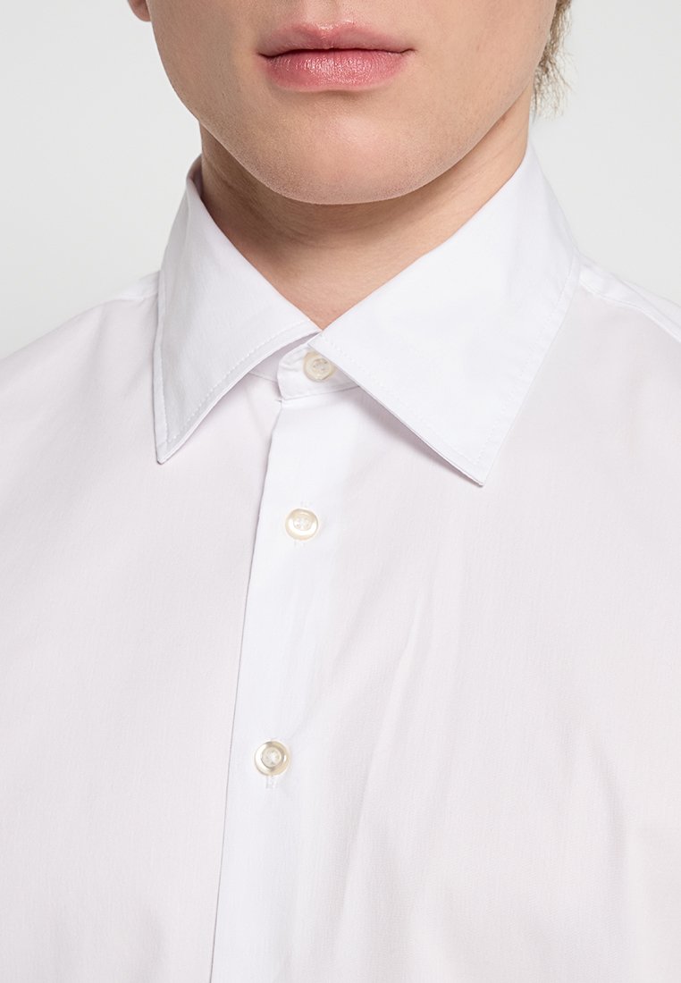 Camicia bianca con colletto tradizionale, dotata di una texture liscia e quattro bottoni, che mostra una leggera lucentezza del tessuto.