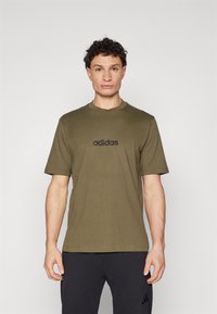 Olivově zelené bavlněné tričko s krátkými rukávy a kulatým výstřihem, s černým logem adidas umístěným na hrudi.
