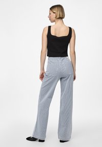 Fekete bordázott cropped top, világoskék, függőleges csíkozású, széles lábú nadrággal párosítva. A szett négyzetes szabású nyakkivágással és laza fit-tel rendelkezik.