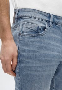 Τζιν παντελόνι σε ανοιχτό μπλε χρώμα με κλασικό σχέδιο πέντε τσεπών. Διαθέτει ελαφρύ ξεθώριασμα, εμφανείς ραφές και δερμάτινο ταμπελάκι στη μέση στο πίσω μέρος.