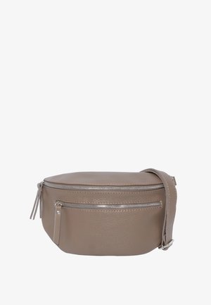 Junge Frau lächelnd, trägt ein schwarzes langärmeliges Oberteil und Jeans, trägt eine taupefarbene Leder-Umhängetasche mit Reißverschlusstaschen.