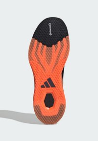 Sål på sportsko med svart og oransje design, strukturert gummi for grep, og "Continental"-merke på en svart seksjon.