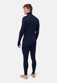 Tmavě modrá termo spodní vrstva s dlouhými rukávy a přiléhavými legínami, vyrobená z měkkého, strukturovaného materiálu s otvory pro palce na manžetách.