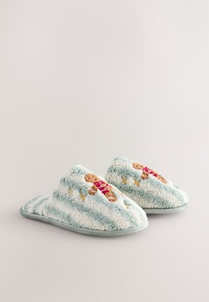 Chaussons duveteux bleu clair avec des rayures blanches, ornés d'une broderie de bonhomme en pain d'épice et en tissu doux et texturé. Semelle en caoutchouc pour une meilleure adhérence.
