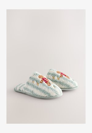 Chaussons duveteux bleu clair avec des rayures blanches, ornés d'une broderie de bonhomme en pain d'épice et en tissu doux et texturé. Semelle en caoutchouc pour une meilleure adhérence.