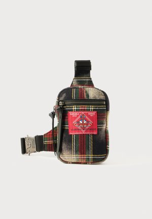 Plaid fabric bag featuring red and green tones, black accents, and a prominent red logo patch. Compact design with a zip closure and adjustable strap.