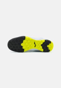 Suola in gomma nera e gialla con tacchetti esagonali, caratterizzata da un design diviso. La parte superiore presenta una texture blu chiaro con dettagli sottili.