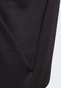 Svart tygdetalj med en mjuk textur, som har diagonala sömmar och en subtil glans. Minimalistisk design, mjukt och flexibelt material.