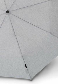 Copertura dell'ombrello di colore grigio chiaro con texture, completamente aperta, con mozzo nero visibile al centro e piccolo'etichetta di tessuto nera sul bordo.