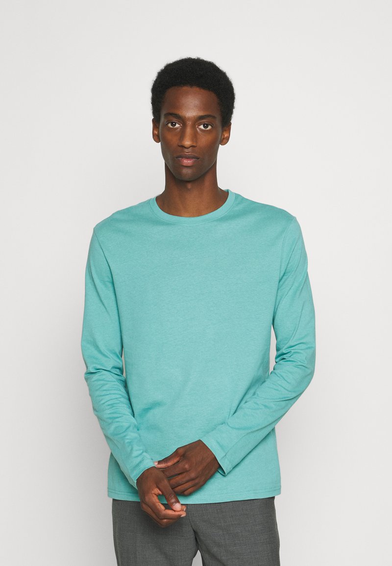 Langarmshirt mit Rundhalsausschnitt aus leichtem türkisen Baumwollstoff, mit glatter Textur und lockerer Passform, ohne sichtbare Muster oder Akzente.