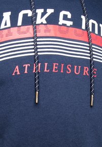 Sudadera de color azul marino con un estampado que presenta franjas horizontales rojas y blancas, texto "ATHLEISURE" y un cordón con extremos metálicos.