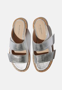 Srebrne metalne sandale na klizanje s dva široka remena i glatkom potplatom. Imaju svijetlosmeđe akcentne detalje i male zakovice duž ruba baze.