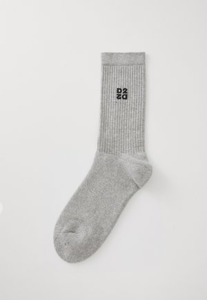 Heledad hall kašmir sokk, millel on must DSQ2 logo tikand peaaegu ülemises ääres, valge taustal.