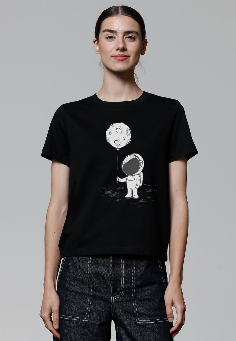 Schwarzes Baumwoll-T-Shirt mit einem grafischen Motiv eines Cartoon-Astronauten, der einen mondförmigen Ballon hält, vor einem schlichten Hintergrund.