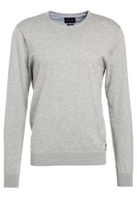 Hellgrauer Langarmpullover aus weichem Stoff. Mit Rundhalsausschnitt und gerippten Bündchen, sowie einem marineblauen Punkte-Muster am inneren Kragen.