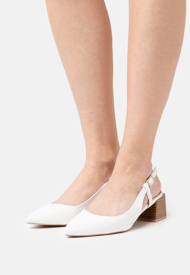 Escarpins blancs à talon slingback avec un bout pointu, fabriqués en matériau lisse. Comprend un talon carré avec une texture en bois et une bride ajustable à la cheville.