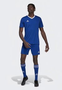 Tricou sportiv albastru cu decolteu în V alb, pantaloni scurți asortați și șosete albastre cu dungi. Are logo-ul Adidas, conceput pentru activități sportive.