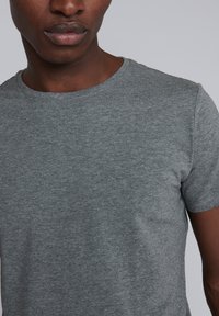 Camiseta gris de manga corta hecha de tela suave, con cuello redondo y un corte relajado, con detalles de costura mínimos.