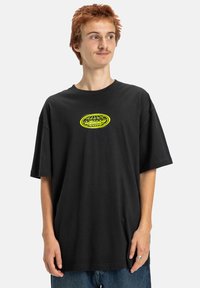 Czarna, oversize koszulka z bawełny, z jasnosłonecznym graficznym logo na piersi. Krótkie rękawy i luźny krój.