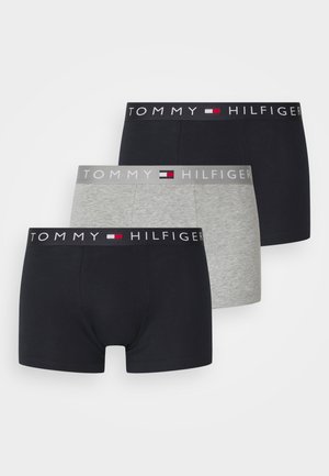 Drei Paar Boxershorts in Schwarz, Marineblau und Grau. Jedes Paar besitzt das Logo "TOMMY HILFIGER" am Bund. Das Material wirkt glatt.
