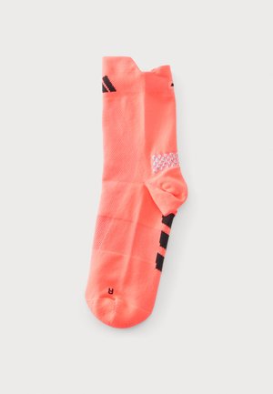 Chaussette de sport corail vif unique avec des rayures noires et un logo, tissu texturé et petits points blancs antidérapants à la cheville.