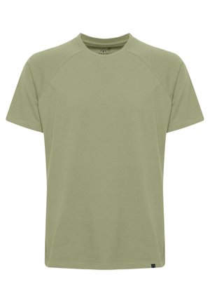 T-shirt vert clair à col rond et manches raglan courtes. Fabriqué en tissu doux et léger. Présente une étiquette en bas à gauche.
