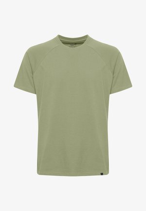 T-shirt vert clair à col rond et manches raglan courtes. Fabriqué en tissu doux et léger. Présente une étiquette en bas à gauche.